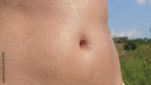 Closeup Of A Tanned Female Belly, Wet With The Droplets