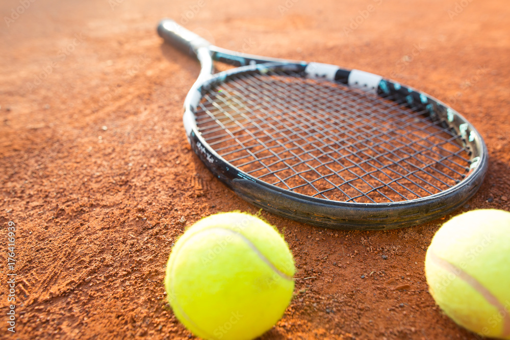 Close up view of tennis racket and balls on the clay tennis court, recreational sport (color toned image)