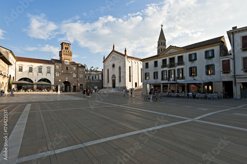 The clock tower or "Torresin" in Piazza Grande in Oderzo and the Cathedral. Ancient city of Roman origin in the province of Treviso, Italy.