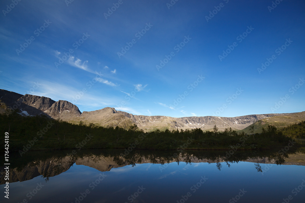 Mountains reflected in the smooth surface of the lake at dawn.
