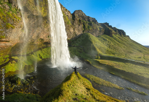 Tourist standing in front of Seljalandsfoss one of the best known waterfalls in southern Iceland  Seljalandsfoss   Iceland