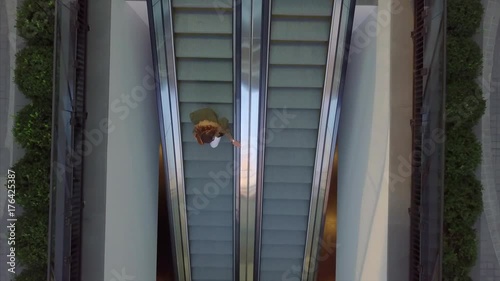 A woman goes down by escalators - Aerial - Bird Eyes