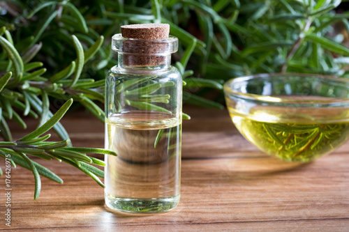 A bottle of rosemary essential oil with fresh rosemary twigs