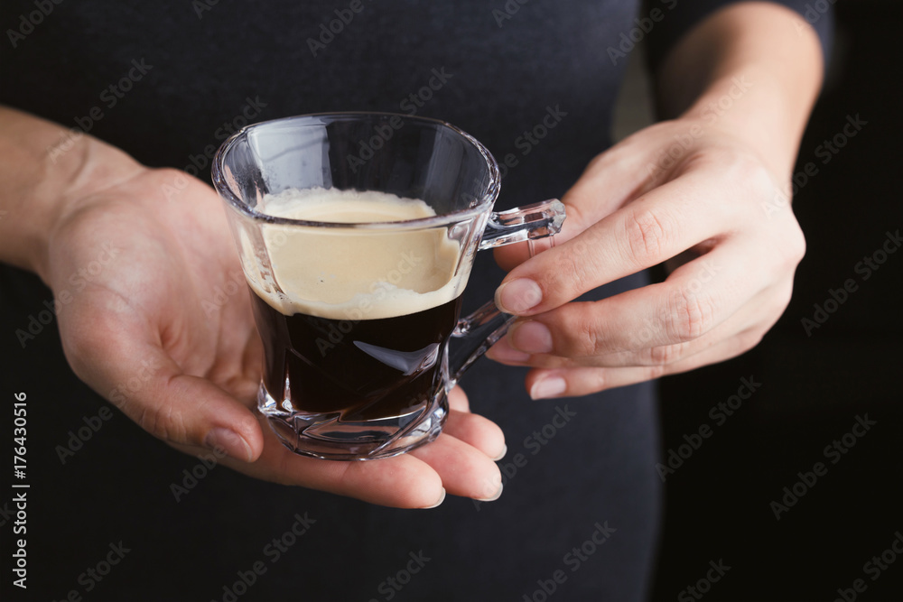 Woman holding espresso coffee in glass cup