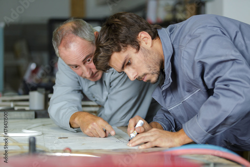 auto mechanic shows trainee how to work