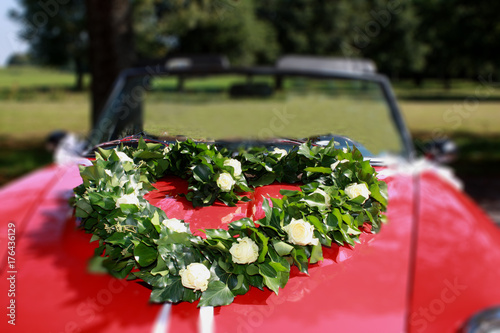 Herz, aus Efeu und weißen Rosen, auf einer roten Motorhaube photo