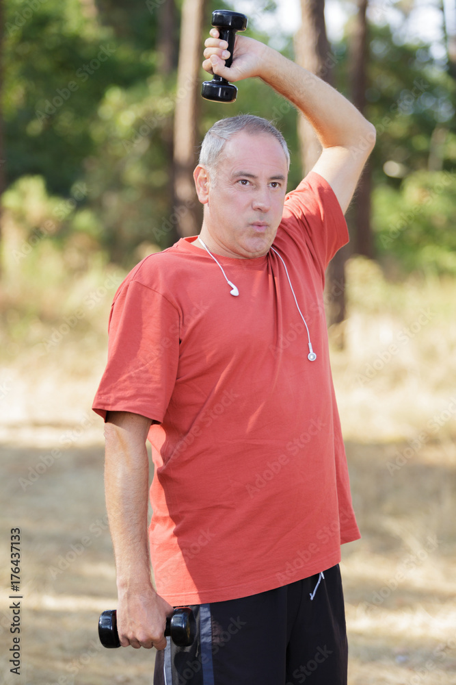 Fototapeta premium mature man exercising with dumbbell at park