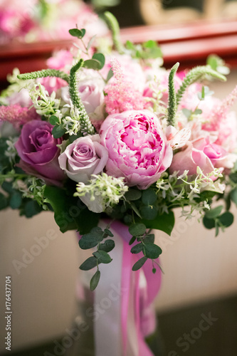 Rustic wedding bouquet with white roses  crimson peonies  and greens on a wooden floor. Indoors.