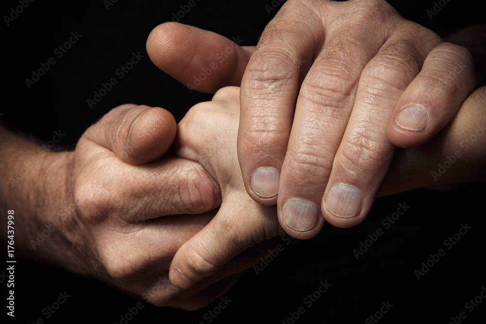 Hands of an elderly man holding the hand of a younger man. Hands of an elderly man holding the hand of a younger man.