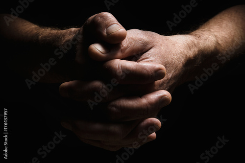 Hands of an elderly man's palms together, thought about problems, with dramatic lighting