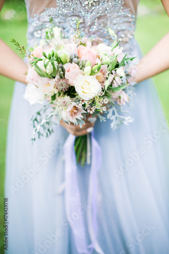 Bride holding wedding bouquet outdoors