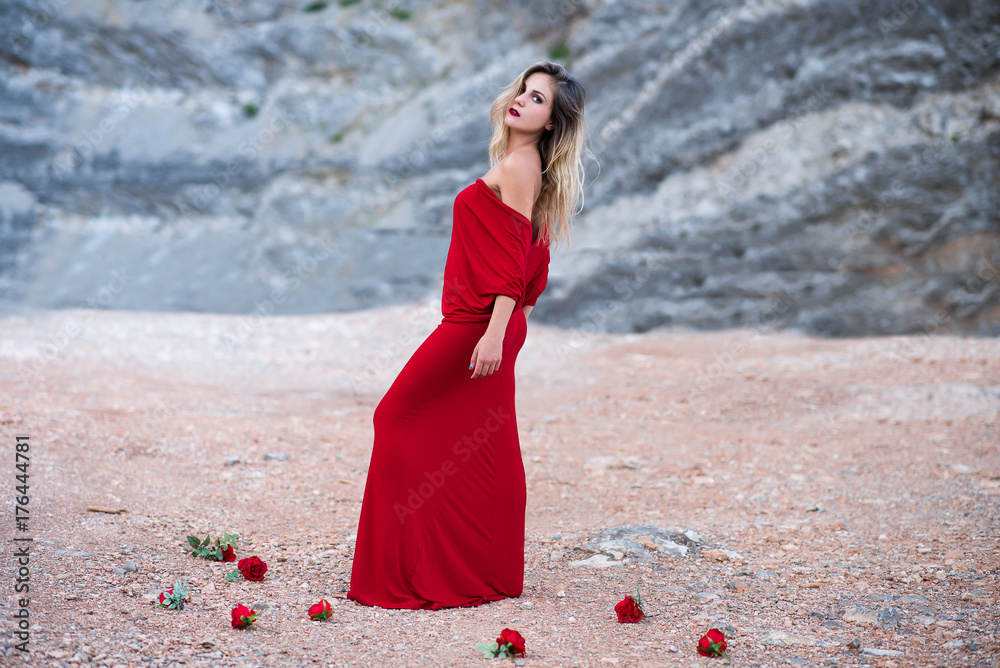 Beautiful young woman model in a maxi red dress outdoors in nature ...