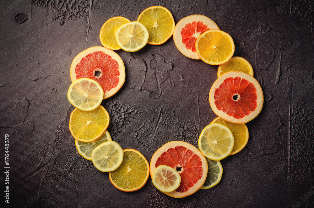 Citrus fruit slices of lemon, orange, grapefruit in circle shape on dark background. Citrus fruit slices of lemon, orange, grapefruit in circle shape on dark background.