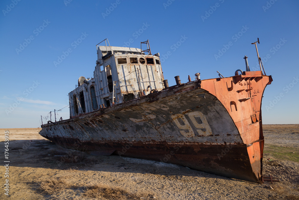 Aral sea disaster. Abandoned rusty fishing boat at the desert on the place of former Aral sea Aral sea disaster. Abandoned rusty fishing boat at the desert on the place of former Aral sea