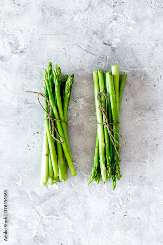 Bunches of fresh asparagus sprouts on grey stone background top view