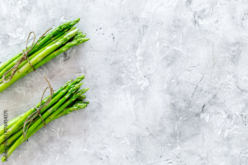 Bunches of fresh asparagus sprouts on grey stone background top view copyspace
