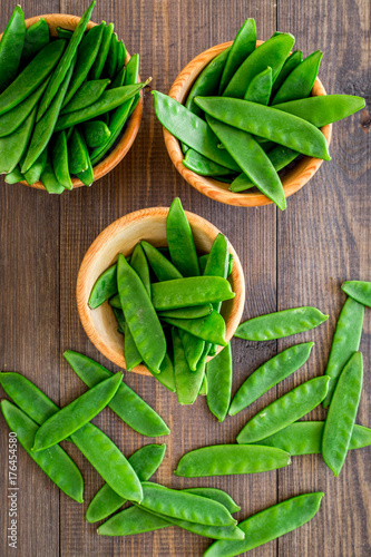 Fototapeta Naklejka Na Ścianę i Meble -  Fresh pea pods in bowls on dark wooden background top view