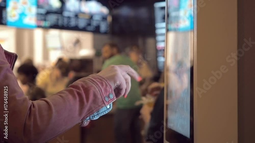 Woman choosing food via self-service machine at fast food restaurant. Girl using self-service touch terminal