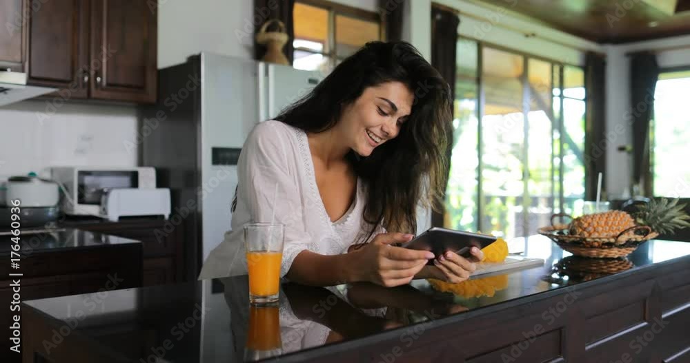 Girl Use Tablet Computer Drink Juice Laughing, Young Woman In Kitchen Studio Modern House Interior Slow Motion 60 Girl Use Tablet Computer Drink Juice Laughing, Young Woman In Kitchen Studio Modern House Interior Slow Motion 60