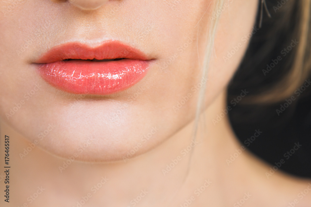 Detail on a gorgeous lips of a beautiful happy blonde woman. Lips are painted with bright red lipstick, skin is soft and natural. Photographed on daylight, isolated on black background. Detail on a gorgeous lips of a beautiful happy blonde woman. Lips are painted with bright red lipstick, skin is soft and natural. Photographed on daylight, isolated on black background.