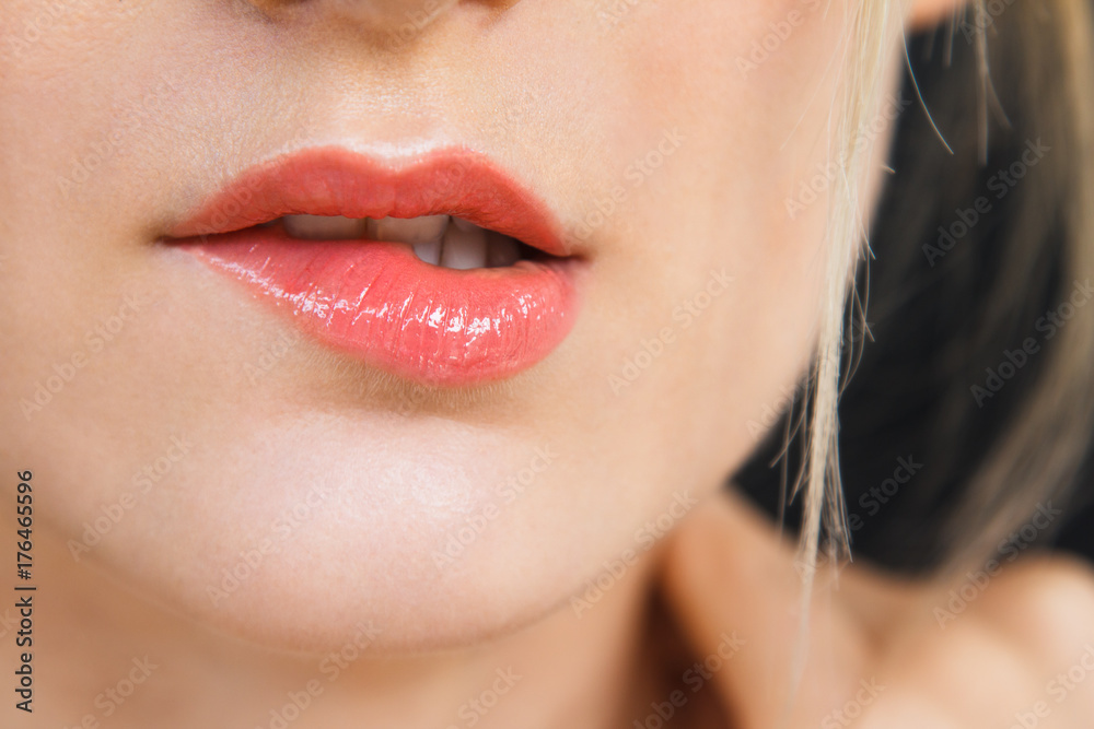 Detail on a gorgeous lips of a beautiful happy blonde woman. Lips are painted with bright red lipstick, skin is soft and natural. Photographed on daylight, isolated on black background. Detail on a gorgeous lips of a beautiful happy blonde woman. Lips are painted with bright red lipstick, skin is soft and natural. Photographed on daylight, isolated on black background.