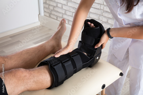 Orthopedist Putting Walking Brace To Patient's Leg photo