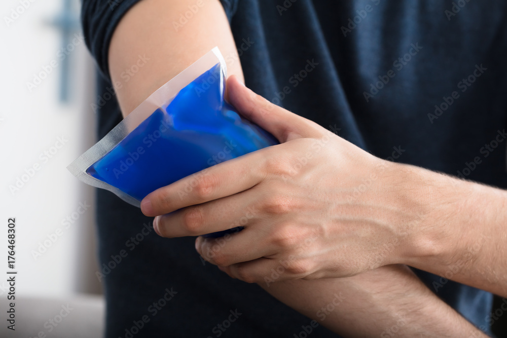 Person Applying Ice Gel Pack On An Injured Elbow