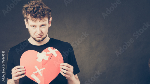 Sad man with glued heart by plaster. photo