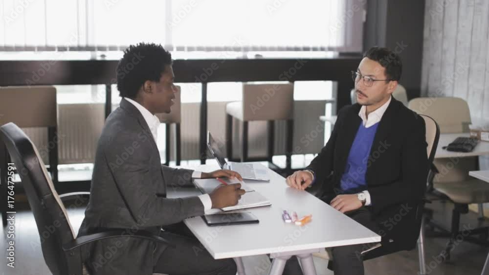 Two men sit in armchairs at the office and talking Two men sit in armchairs at the office and talking
