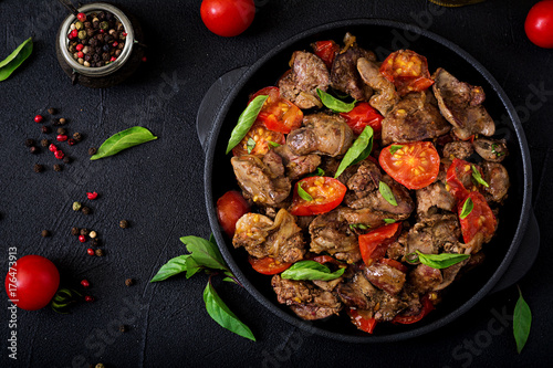 Chicken liver (offal) with onions and tomatoes in a frying pan in Armenian. Flat lay. Top view