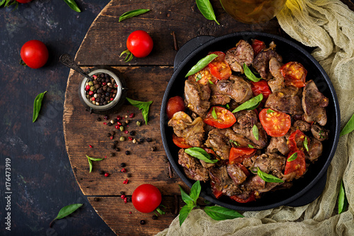 Chicken liver (offal) with onions and tomatoes in a frying pan in Armenian. Flat lay. Top view photo