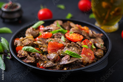 Chicken liver (offal) with onions and tomatoes in a frying pan in Armenian