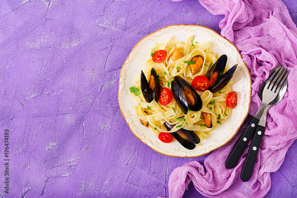 Seafood fettuccine pasta with mussels over black background. Mediterranean delicacy food. Flat lay. Top view