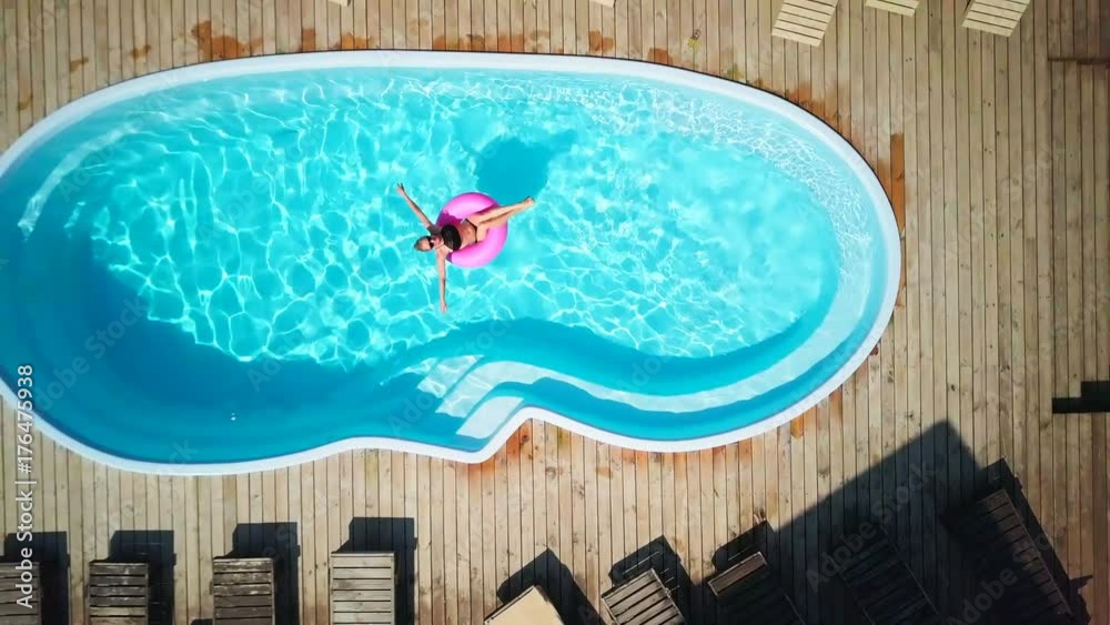 Top view fit girl enjoy pool in swimming circle sunny day sunrise drone footage