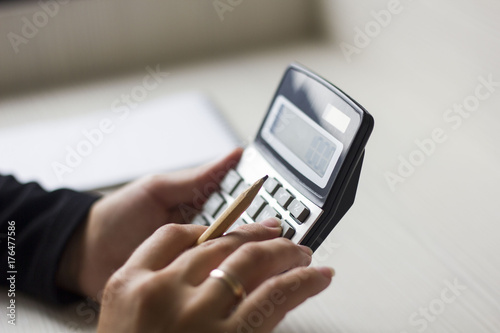 female hands counting on calculator and holding a pencil