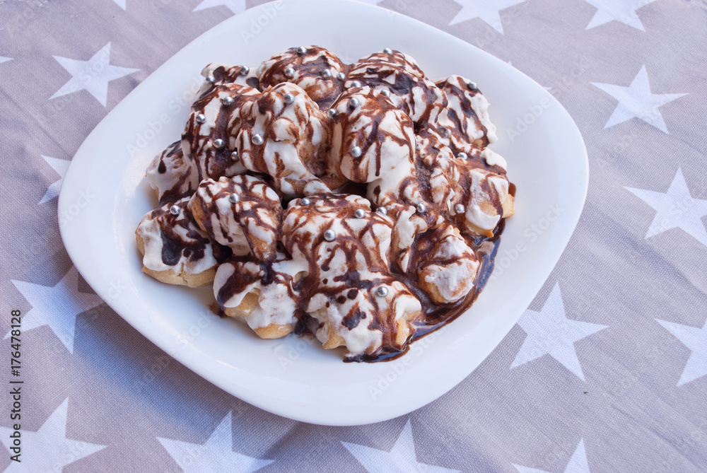Christmas, new year cake from profiteroles with chocolate on fabric with stars. Christmas, new year cake from profiteroles with chocolate on fabric with stars.
