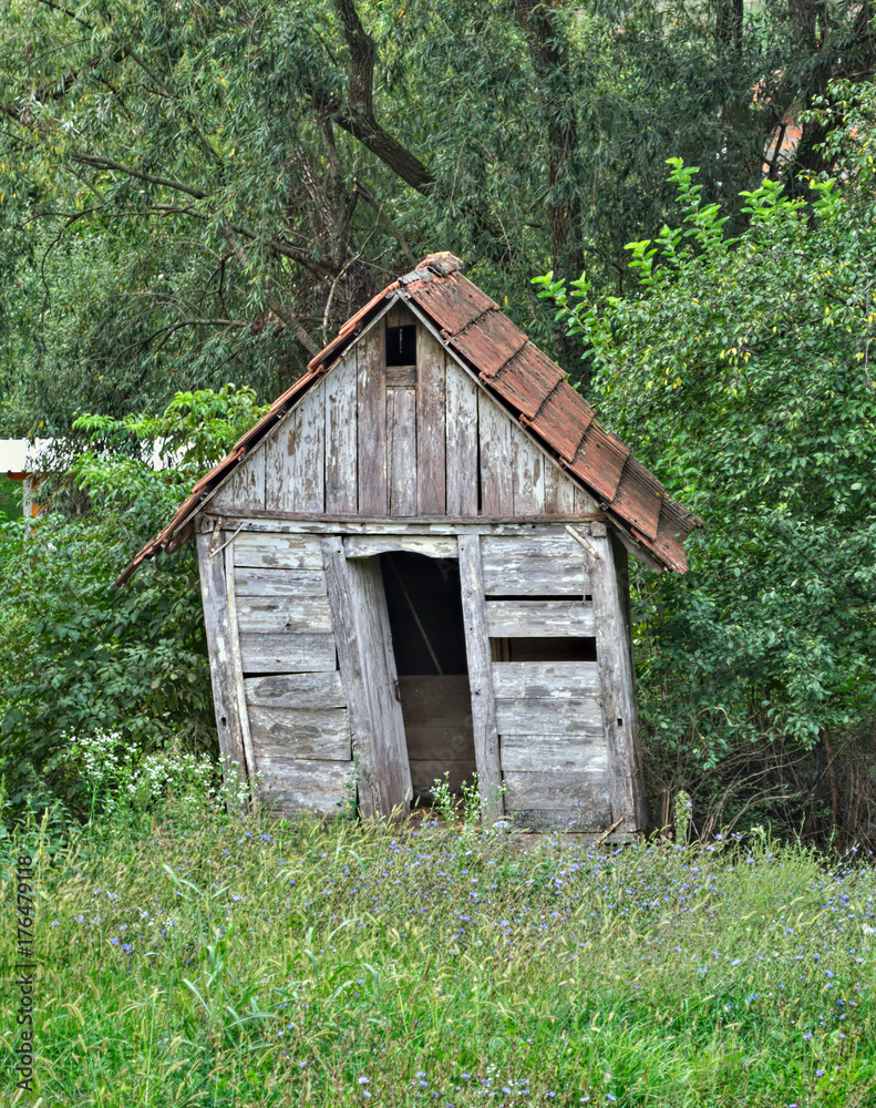 Small abandoned wooden cabin surrounded by trees Small abandoned wooden cabin surrounded by trees