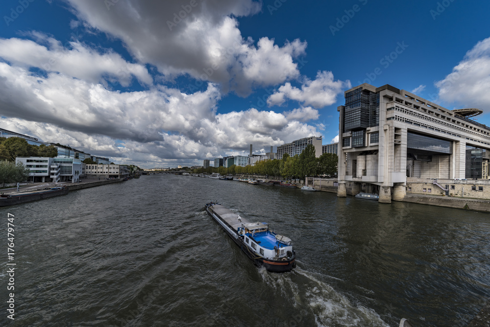 Good transportation boat sailing along the Seine river, in front the French finance ministery building under a sunny sky day
