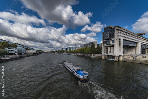 Good transportation boat sailing along the Seine river  in front the French finance ministery building under a sunny sky day