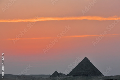 Dramatic sunset behind distant Egyptian pyramids in Giza  Cairo  Egypt
