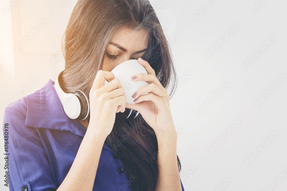 close up of pretty woman relaxing with music by headphone and drinking coffee beside window in the morning close up of pretty woman relaxing with music by headphone and drinking coffee beside window in the morning