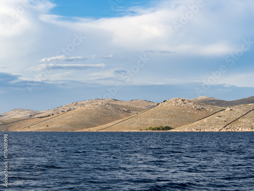 Sailing on a yacht along the landscape of rocky and wavy desert islands in Kornati national park in summer Croatia, Mediterranean sea