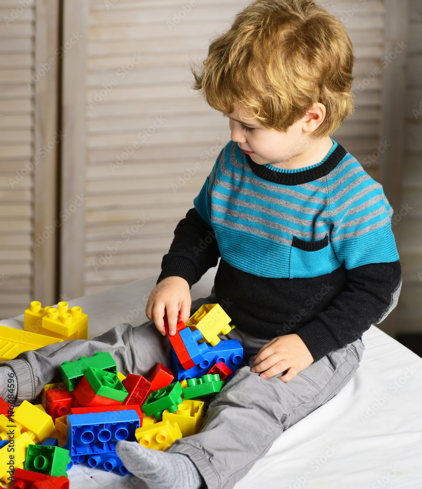 Kid builds of plastic blocks. Childhood and educational activities concept Kid builds of plastic blocks. Childhood and educational activities concept
