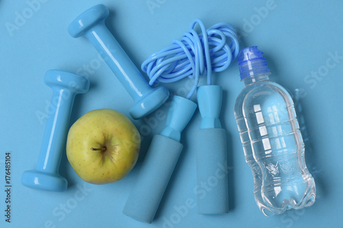 Dumbbells and skipping rope in cyan color on blue background
