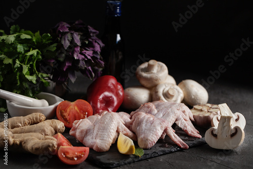 Fresh chicken wings with vegetables on a dark background