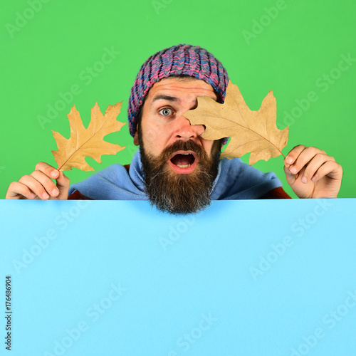 Man in warm hat closes eyes with oak tree leaves
