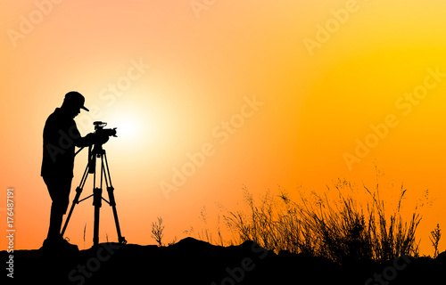 Silhouette of photographer with his camera on sunrise  background.