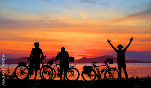 Silhouette man and bike relaxing with  colorful sunrise background.