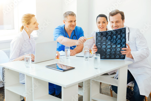 Cheerful medical professionals counseling over MRI scan image at work