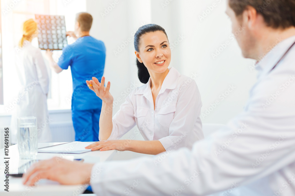 Amazed female doctor smiling while chatting with colleague
